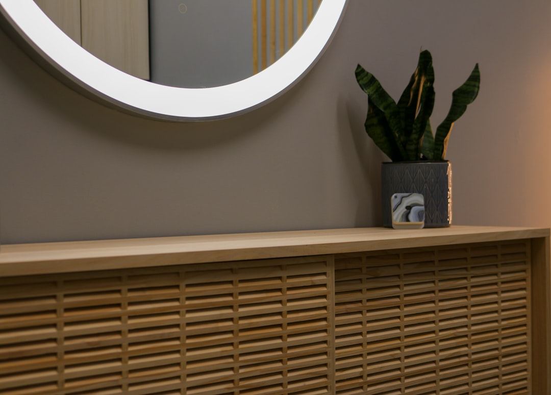 a round mirror on a wall above a wooden cabinet